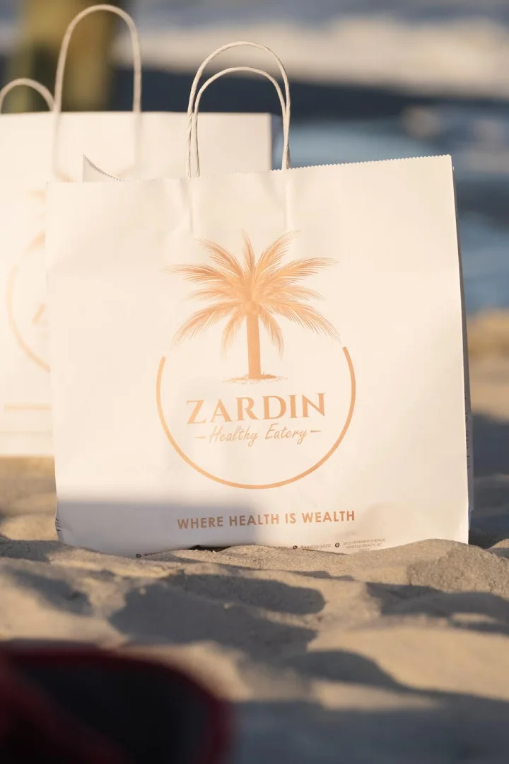 Zardin Healthy Eatery branded takeout bag on the beach